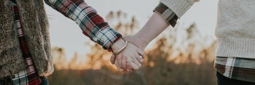 two hands holding in sunny sky