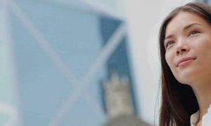 business woman happy stands beside tall building