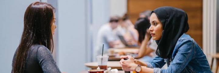 two women sits in office talking to each other