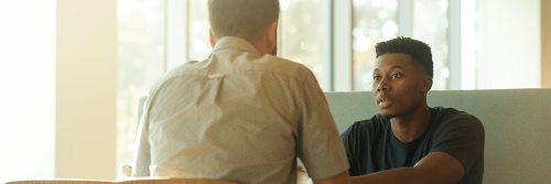 two men sits in library talking resolving conflict