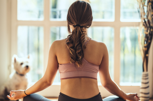 Woman practicing mindfulness and self-care with dog and in exercise clothes