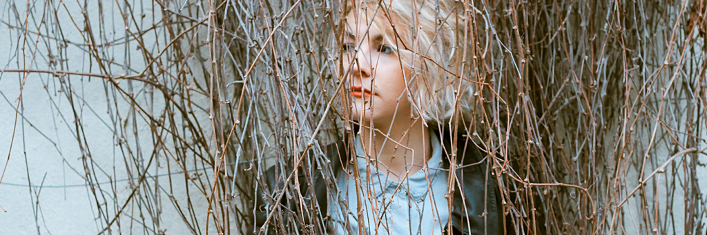 woman sadly stands between trees