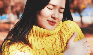 woman wearing yellow scarf eyes closed arms crossed enjoying gratitude life in park