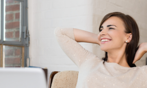young woman sits alone in office smiles looks outside window