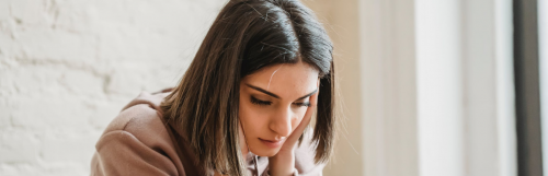 woman with sad face hands on face looks downward