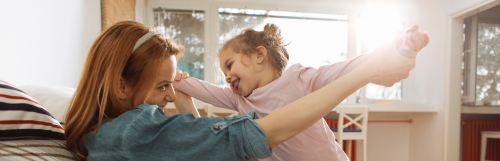 young lady plays with little adorable daughter in living room