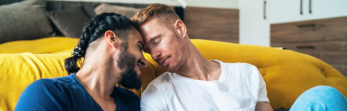 two men sits next to yellow blanket bed enjoy happy moments