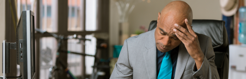 bold man hand on head focuses on thinking sits alone in office