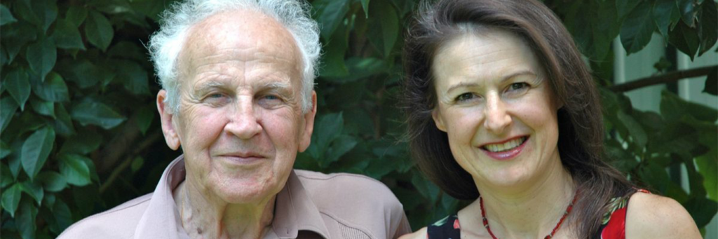 father stands beside daughter smiling posing for photos
