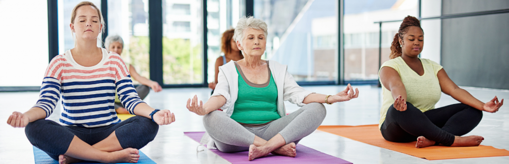 group of five ladies with different ages sit leg crossed meditate peacefully